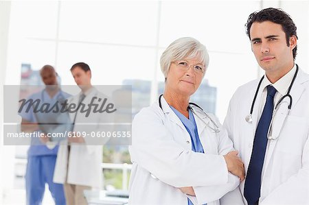 Confident doctors with two colleagues behind them