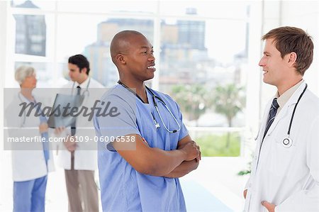 Ärzte mit zwei Kollegen hinter ihnen im Gespräch