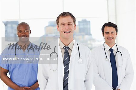 Three smiling doctors standing in front of a window