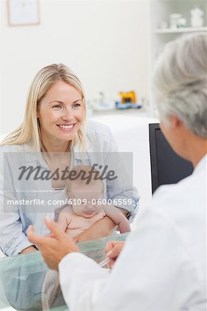 Femme souriante avec son petit bébé Voir le médecin