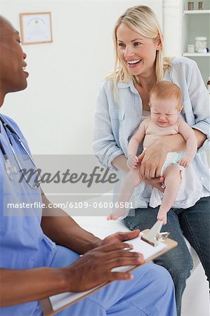 Mère souriante avec son petit bébé visitant le médecin
