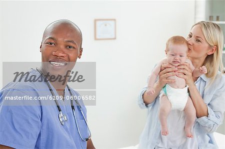 Smiling doctor with mother and her little baby next to him