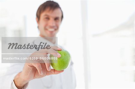 Schöner grüner Apfel, gehalten von einem Chirurgen vor einem Fenster