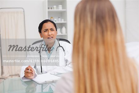 Schwere Praktiker im Gespräch mit ihrer Patientin beim sitzen an ihrem Schreibtisch