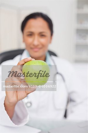 Beautiful green apple being held by a nurse sitting in a medical office
