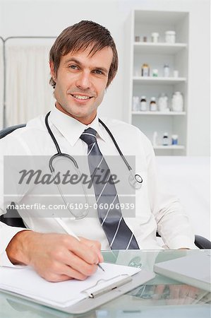 Happy practitioner looking at the camera while working with his clipboard