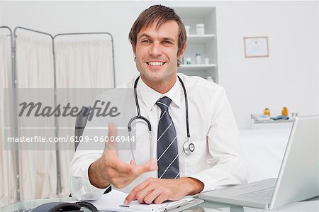 Smiling practitioner offering a hand while looking straight at the camera in his office