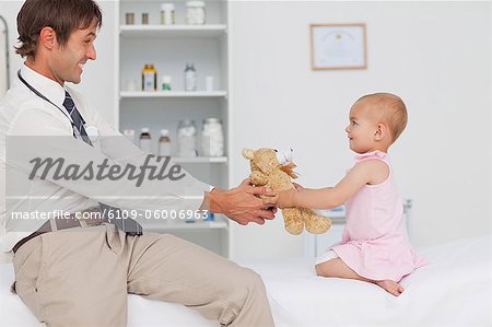 Kleines Baby und ihr Arzt Spaß durch das Spiel mit einem Teddybär