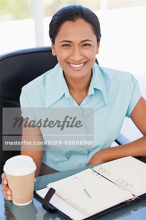 Sekretärin am Schreibtisch sitzend, beim zeigen eines strahlenden Lächeln vor der Kamera