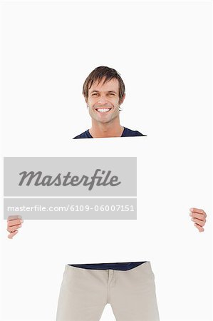 Lächelnder Mann hält ein leeres Plakat vor einem weißen Hintergrund