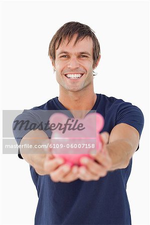 Homme tenant une tirelire rose fond blanc souriant