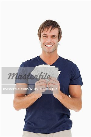 Fan de billets de banque qui s'est tenue par un homme souriant sur fond blanc