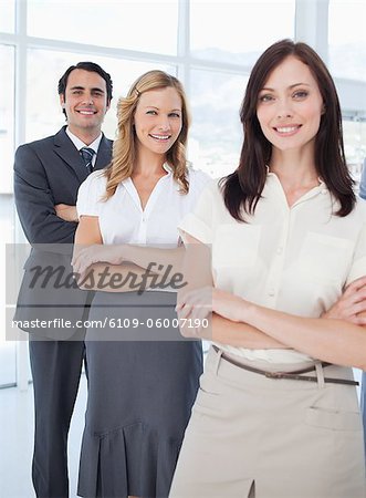 Two women and a man smiling as they stand behind each other with their arms crossed