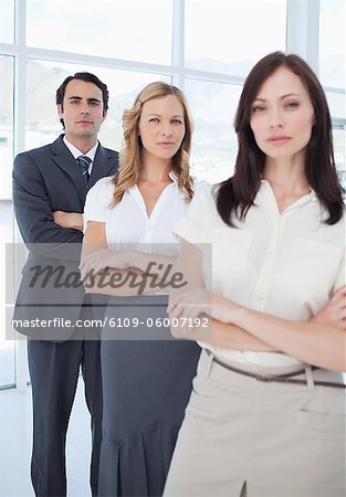 Two women and a man standing behind each other with serious expressions on their faces