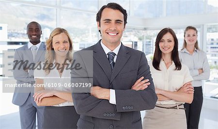 Businessman smiling with his arms crossed as he stands with his colleagues