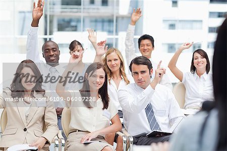 A group of colleagues raising their arms while watching a speaker