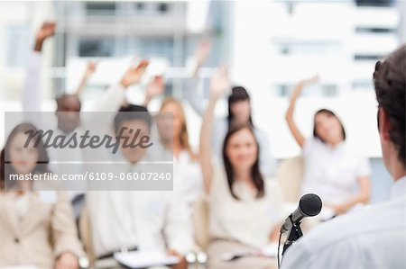 Businessman looking ahead as he gives a speech to his colleagues who have their arms raised