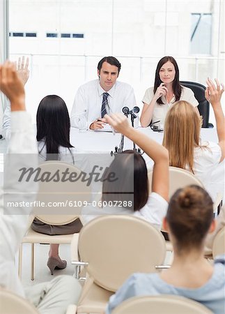 Two business people looking towards an audience who have their arms raised