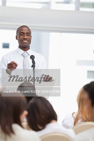 Close-up of a businessman as he gestures towards an audience who is watching him