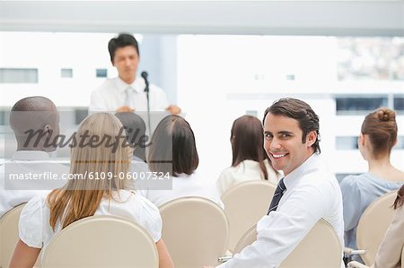 Homme d'affaires souriant en regardant derrière lui lors d'un discours