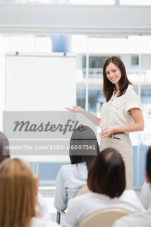 Woman smiling as she gives a presentation to an audience