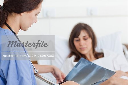 Nurse looking at an x-ray scan with a patient who is in a bed