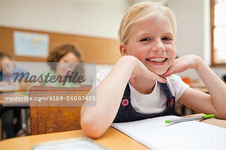 Smiling little girl sitting at desk in class