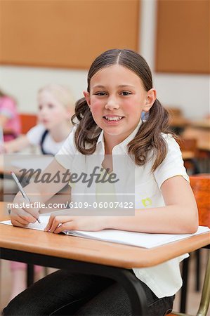 Sourire de petite fille à son pupitre à l'école