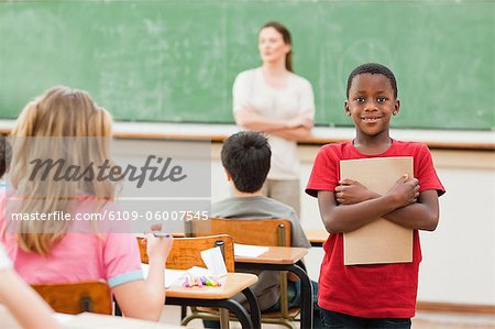 Grundschüler stehen in der Klasse mit seinem Schulheft