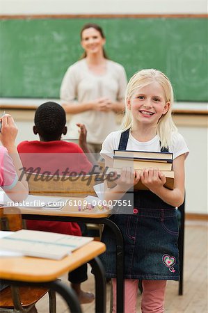 Smiling little girl with stack of books