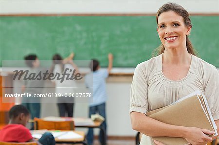 Elementary teacher with students working on blackboard behind her