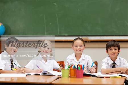 Smiling little schoolchildren sitting at desk together