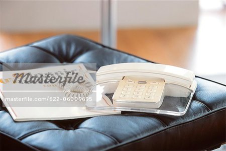 Téléphone et un ouvrage sur la chaise en cuir