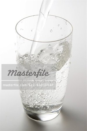 Wasser gießen in Glas mit einfarbigen Hintergrund