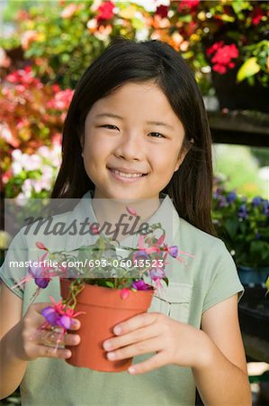 Young girl holding potted flowers in plant nursery, portrait