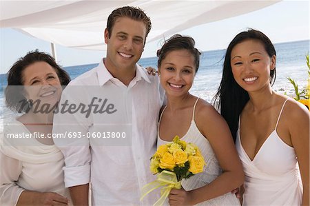 Bride and groom with family at beach wedding, (portrait)