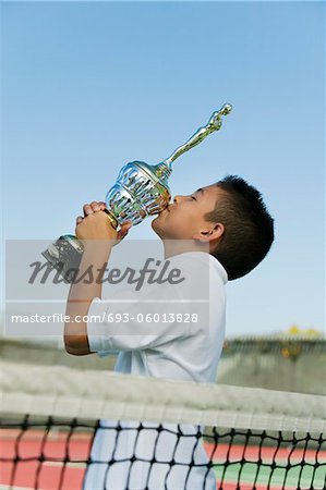 Junge Tennisspieler von Net auf Hof küssen Trophäe, Seitenansicht