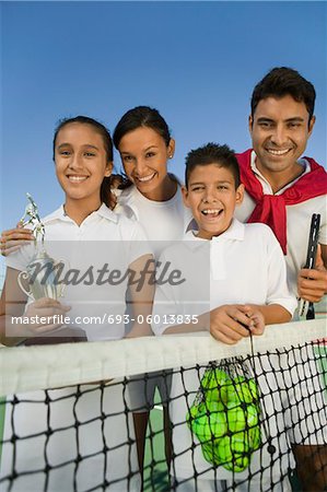 Tennis famille au filet sur le court de tennis, trophée tenue fille, portrait