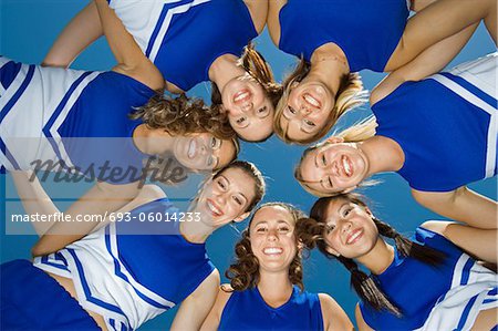 Smiling Cheerleaders standing in circle, (portrait), (view from below)