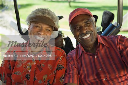 Senior couple sitting in golf cart, smiling, (portrait)