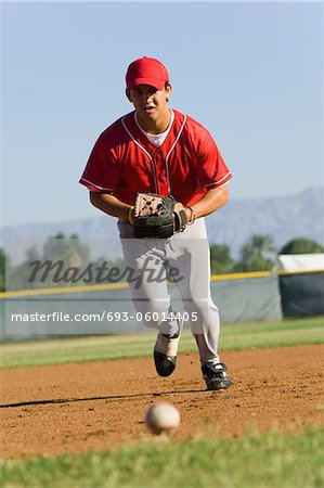 Voltigeur de baseball en courant vers la balle sur le sol