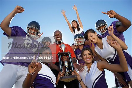 Entraîneur de football, les joueurs et les pom-pom girls, tenant le trophée à l'extérieur, vue faible angle, portrait, (portrait)