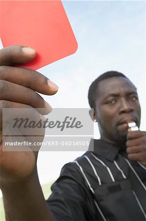 Arbitre de soccer miroiter carton rouge et sifflet gonflant, portrait