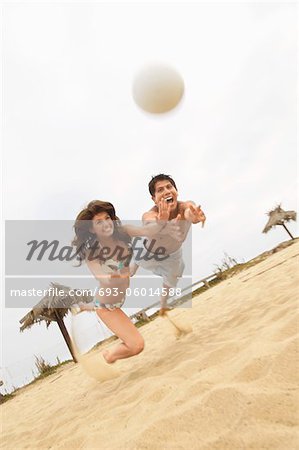 Couple Diving for Volleyball on Beach, tilt view