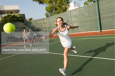 Tennis Player Reaching to hit tennis ball on tennis court
