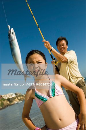 Man showing fish to daughter (7-9) at ocean