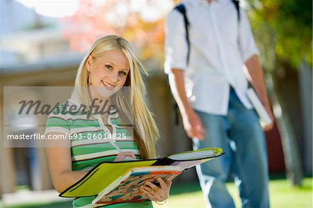 Student writing in notebook, outdoors, (portrait)
