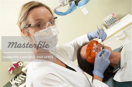 Dentist examining female patient in surgery, (portrait)