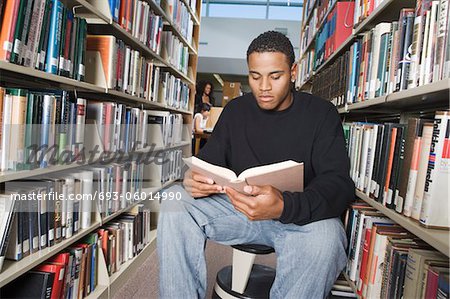 Male student sitting, reading in library