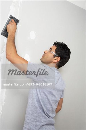 Man sanding interior wall